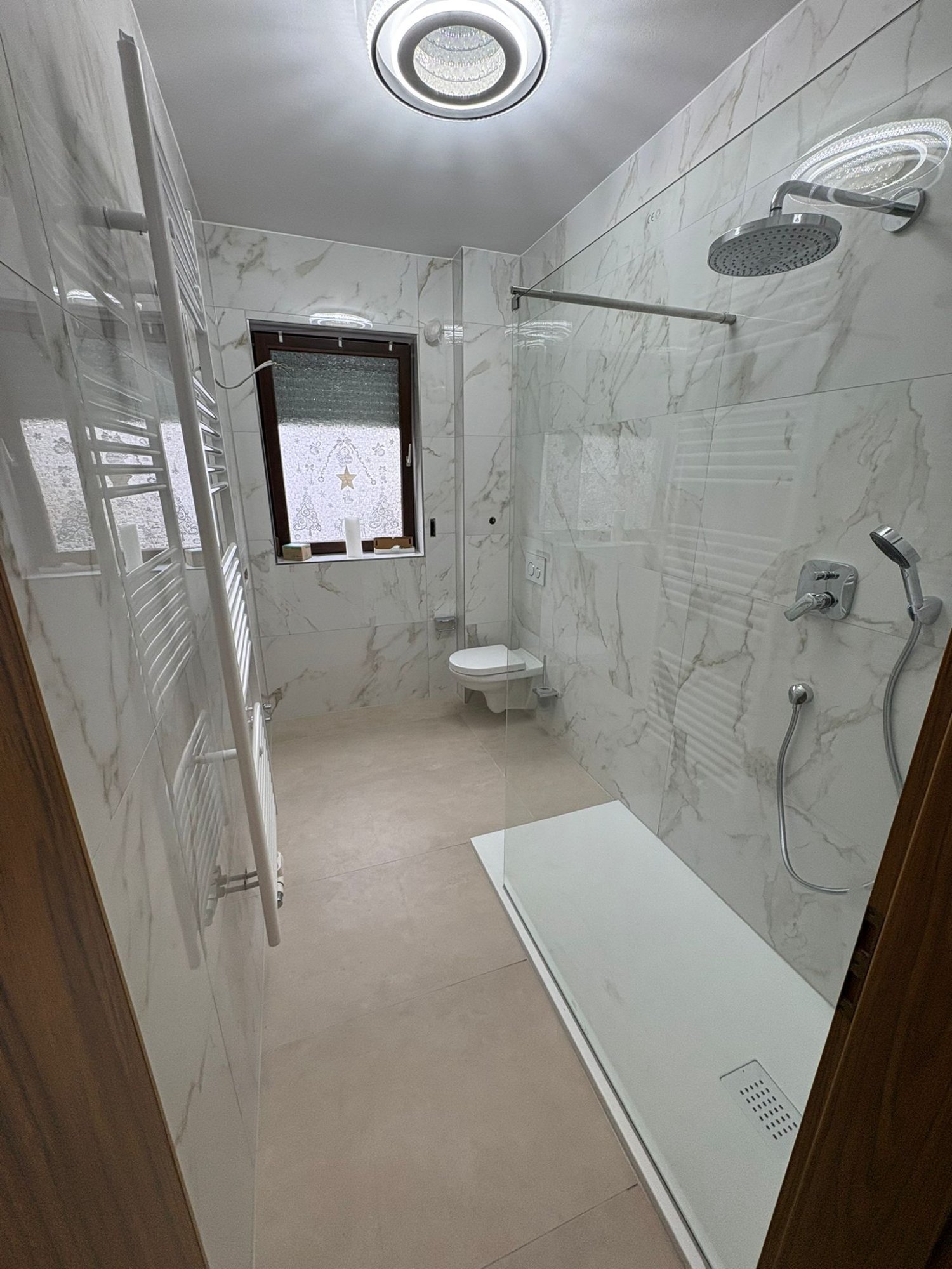 Barrierefreie Dusche mit Marmorfliesen und Regendusche – Baduvia Badumbau